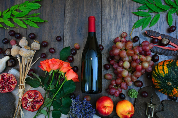 Bouteille de vin au milieu de fleurs, fruits et légumes