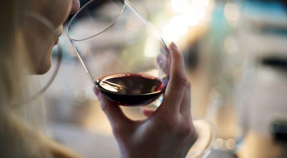 une femme sent le vin et met son nez dans le verre pour détecter les arômes